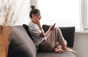 Young woman looking at phone and resting on couch at home